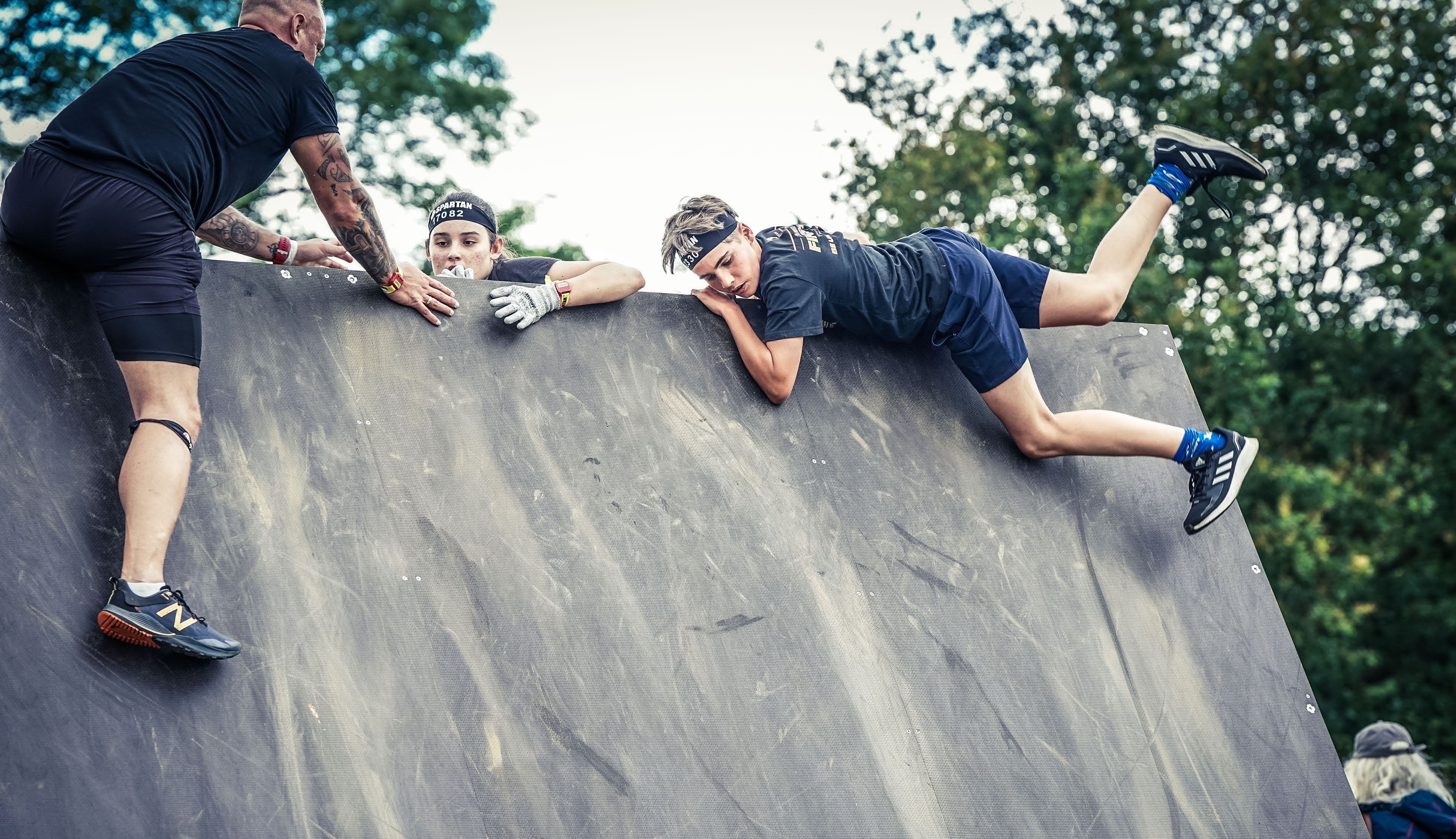 Tom climbing a steep wall during a Spartan race